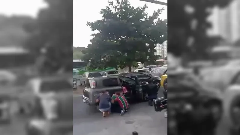Pessoas se protegem atrás de carro durante tiroteio na Mangueira.
